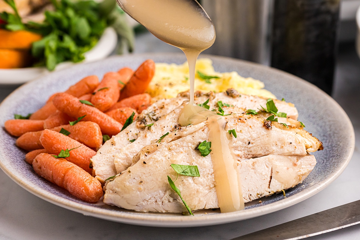 spoon pouring gravy over sliced roast turkey breast