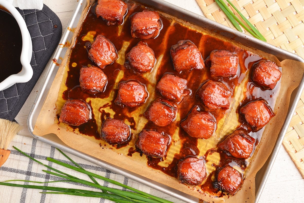 overhead shot of brown sugar bacon wrapped kielbasa bites on a sheet pan