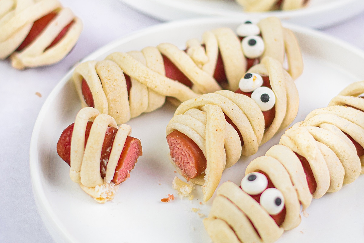 close up shot of mummy hot dog cut in half on plate