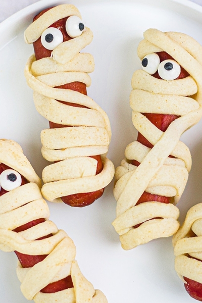 close up overhead shot of four mummy hot dogs on plate