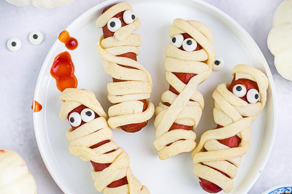 close up overhead shot of four mummy hot dogs on plate