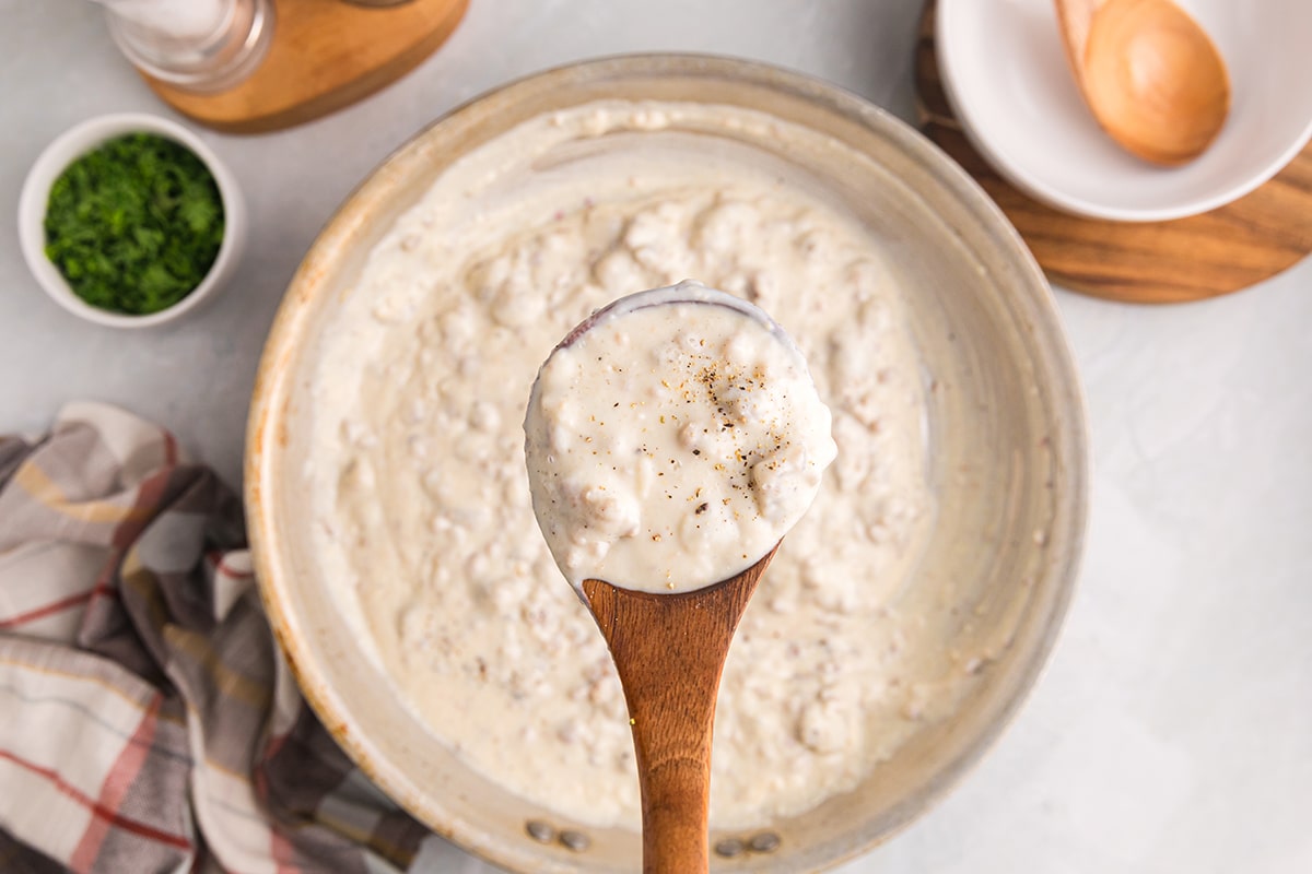 overhead shot of spoon over pan of sausage gravy