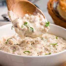 close up of wooden spoon in bowl of sausage gravy