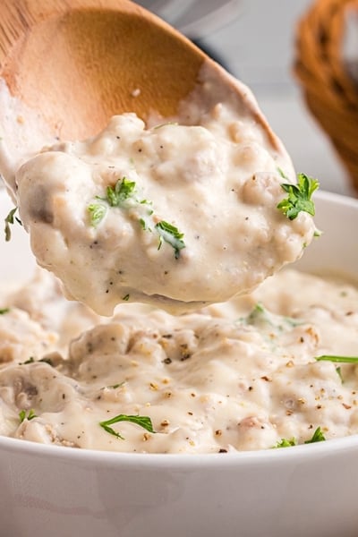 close up of wooden spoon in bowl of sausage gravy