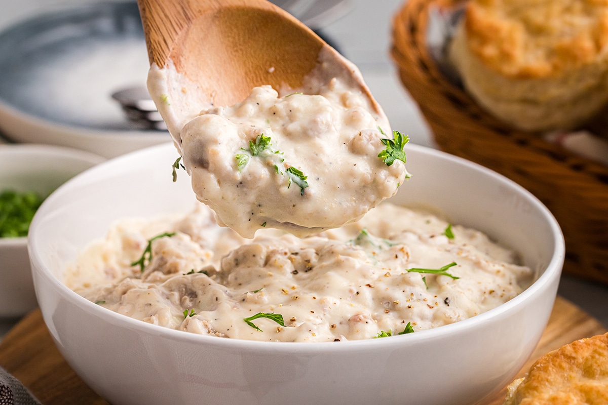 close up of wooden spoon in bowl of sausage gravy