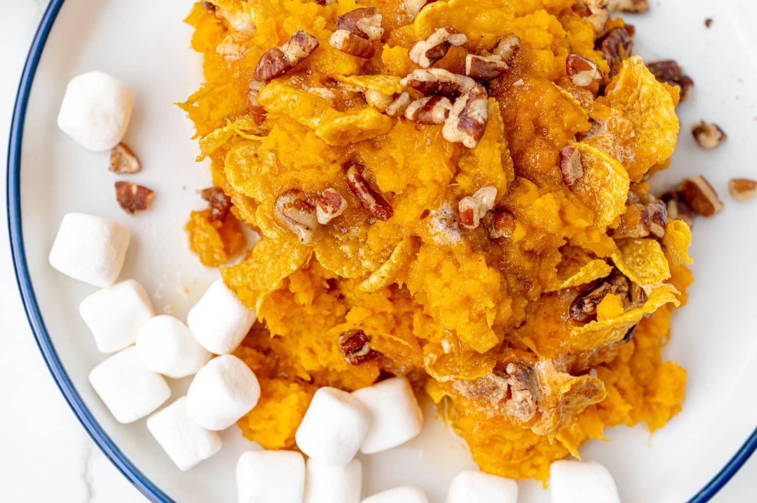 close up of sweet potato casserole on a white serving plate with mini marshmallows