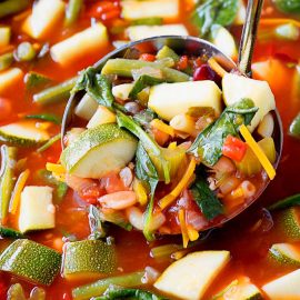 close up of minestrone soup in a ladle