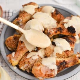 spoon adding white sauce to wings