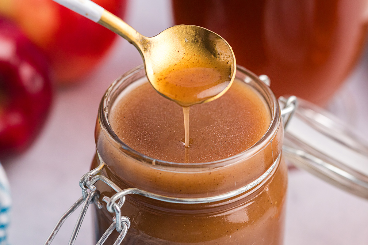 close up of spoon in jar of apple cider syrup