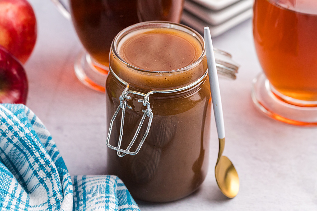 angled shot of jar of apple cider syrup with spoon