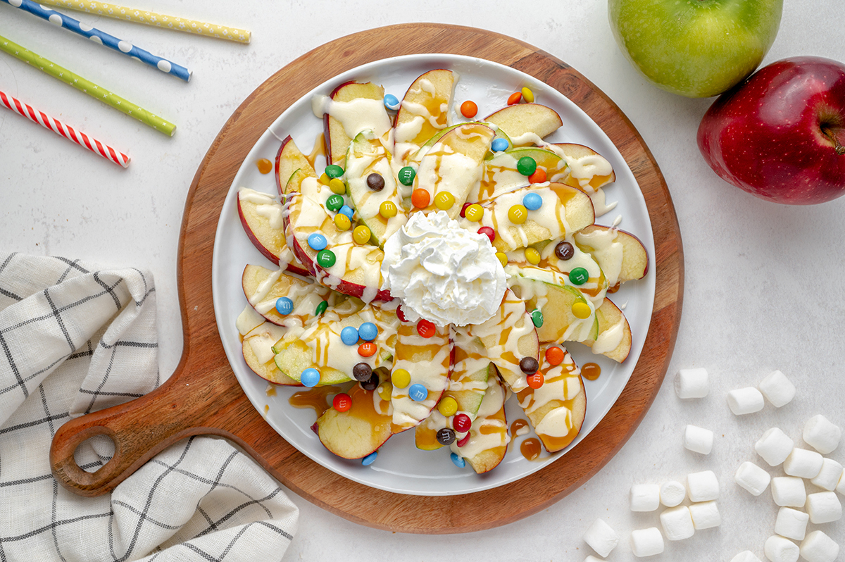 overhead plate of apple slices drizzled with caramel, fluff and min M&Ms
