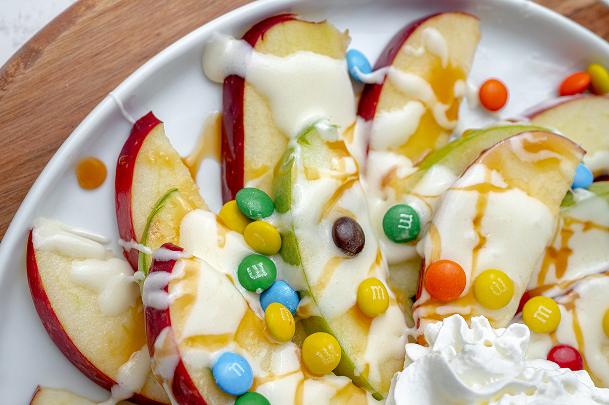 close up of apple nachos with sauces and candy