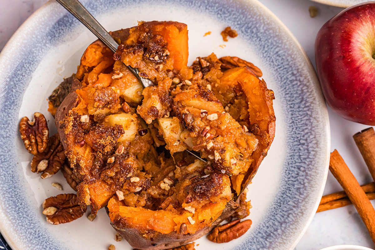 overhead shot of fork taking bite of apple spiced stuffed sweet potato