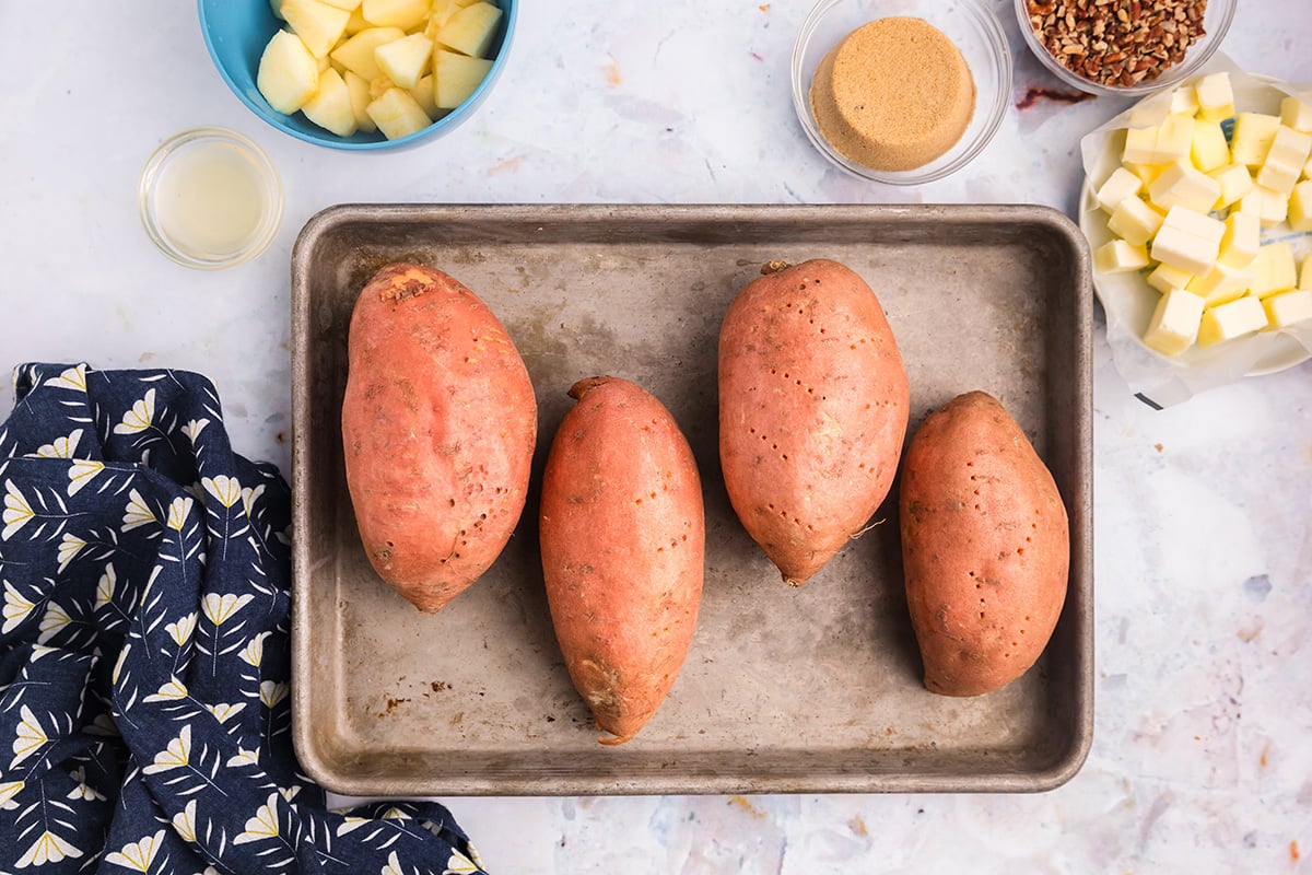 overhead shot of four sweet potatoes on baking sheet