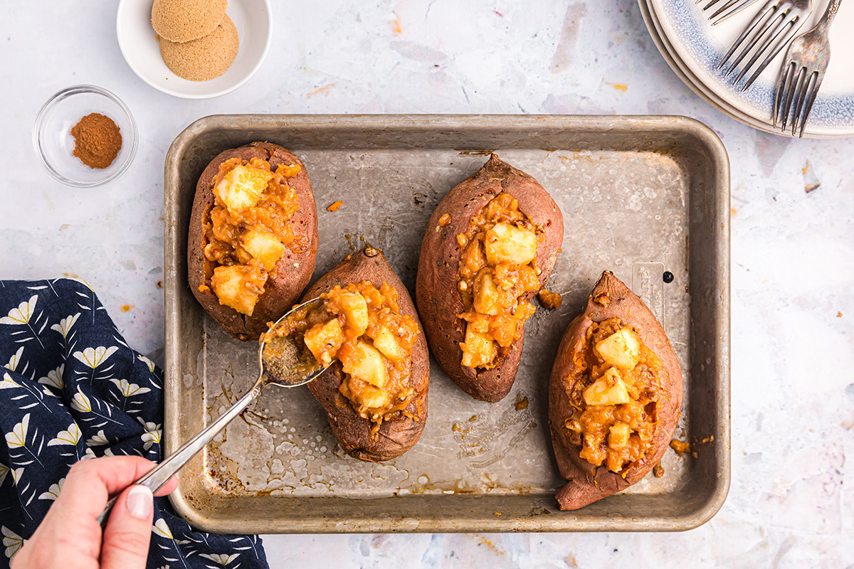 spoon adding stuffing to sweet potatoes