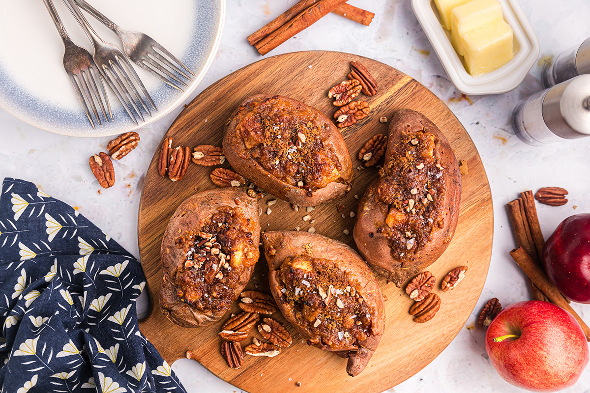 overhead shot of apple spiced stuffed sweet potatoes on round wooden board