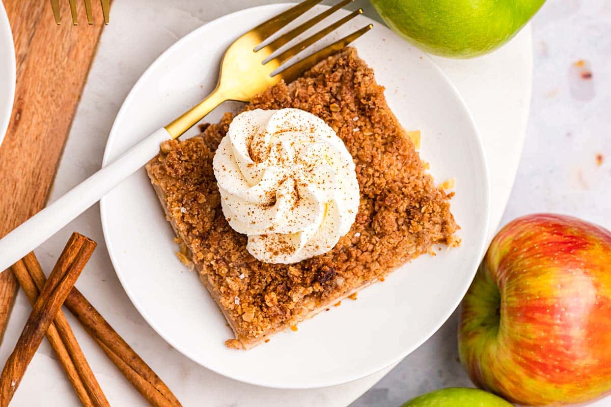 overhead shot of slice of apple slab pie topped with whipped cream