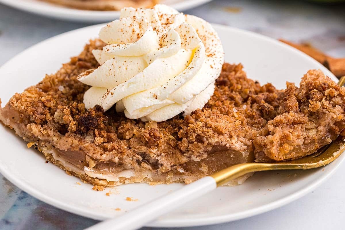 close up of cite taken out of apple slab pie topped with whipped cream