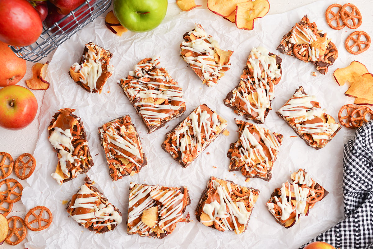 pieces of caramel apple bark on parchment paper with pretzels