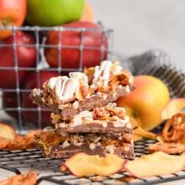 side view of stack of 3 pieces of bark with pretzels, apples, caramel and apples