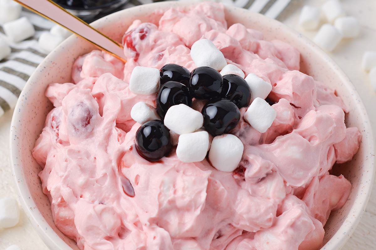 close up angled shot of spoon in bowl of cherry fluff without pineapple