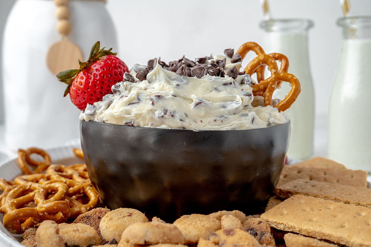 bowl of dessert dip with a fresh strawberry and pretzels