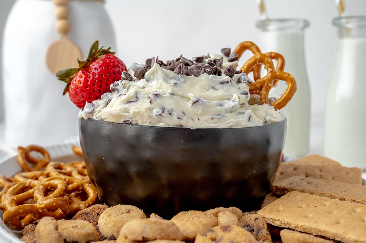 bowl of dessert dip with a fresh strawberry and pretzels