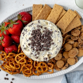 overhead bowl of chocolate chip cookie dough dip with cookies, strawberries, crackers and pretzels