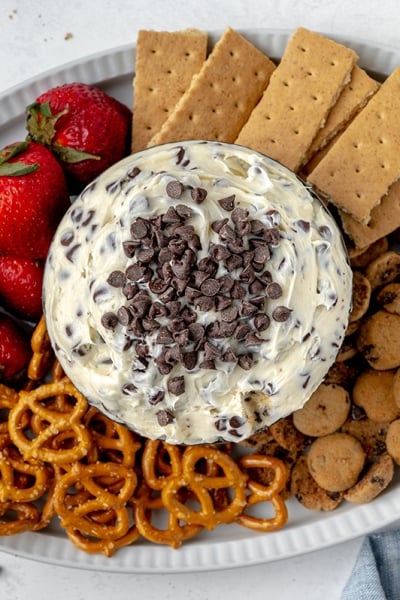 overhead bowl of chocolate chip cookie dough dip with cookies, strawberries, crackers and pretzels