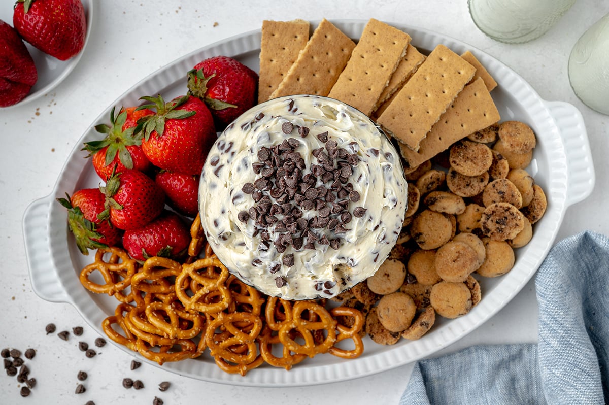 overhead bowl of chocolate chip cookie dough dip with cookies, strawberries, crackers and pretzels