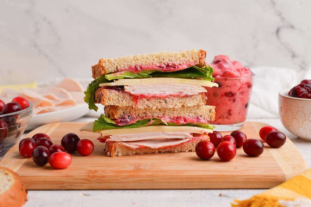 stacked turkey sandwich with cheese, lettuce and cranberry aioli
