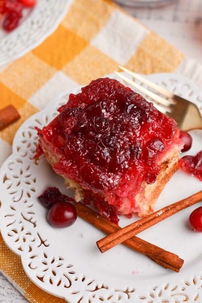 angled shot of cranberry cinnamon roll on plate with fork and cinnamon sticks