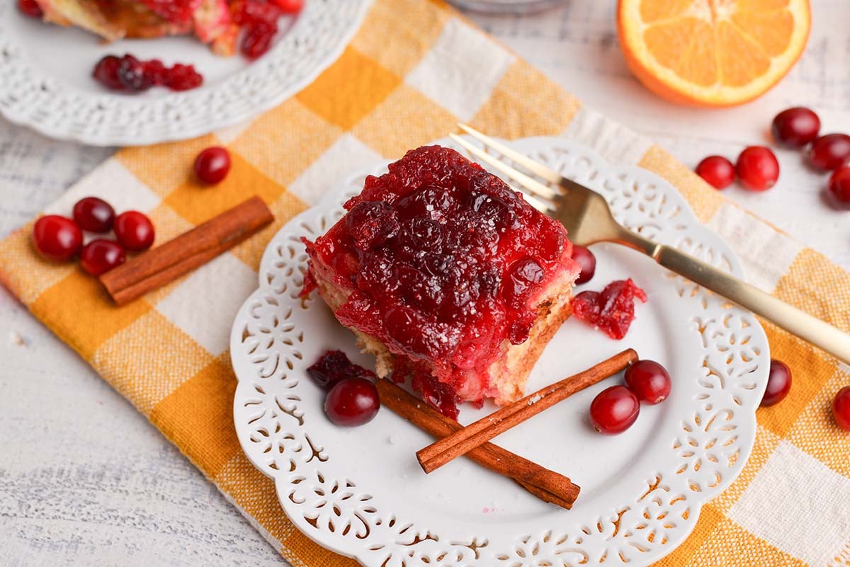 angled shot of cranberry cinnamon roll on plate with fork and cinnamon sticks