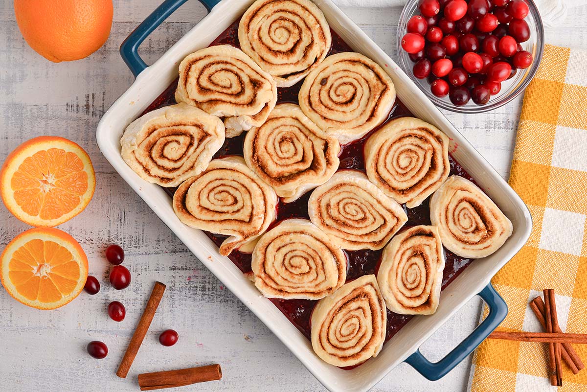 overhead shot of raw cinnamon rolls in pan of cranberry topping