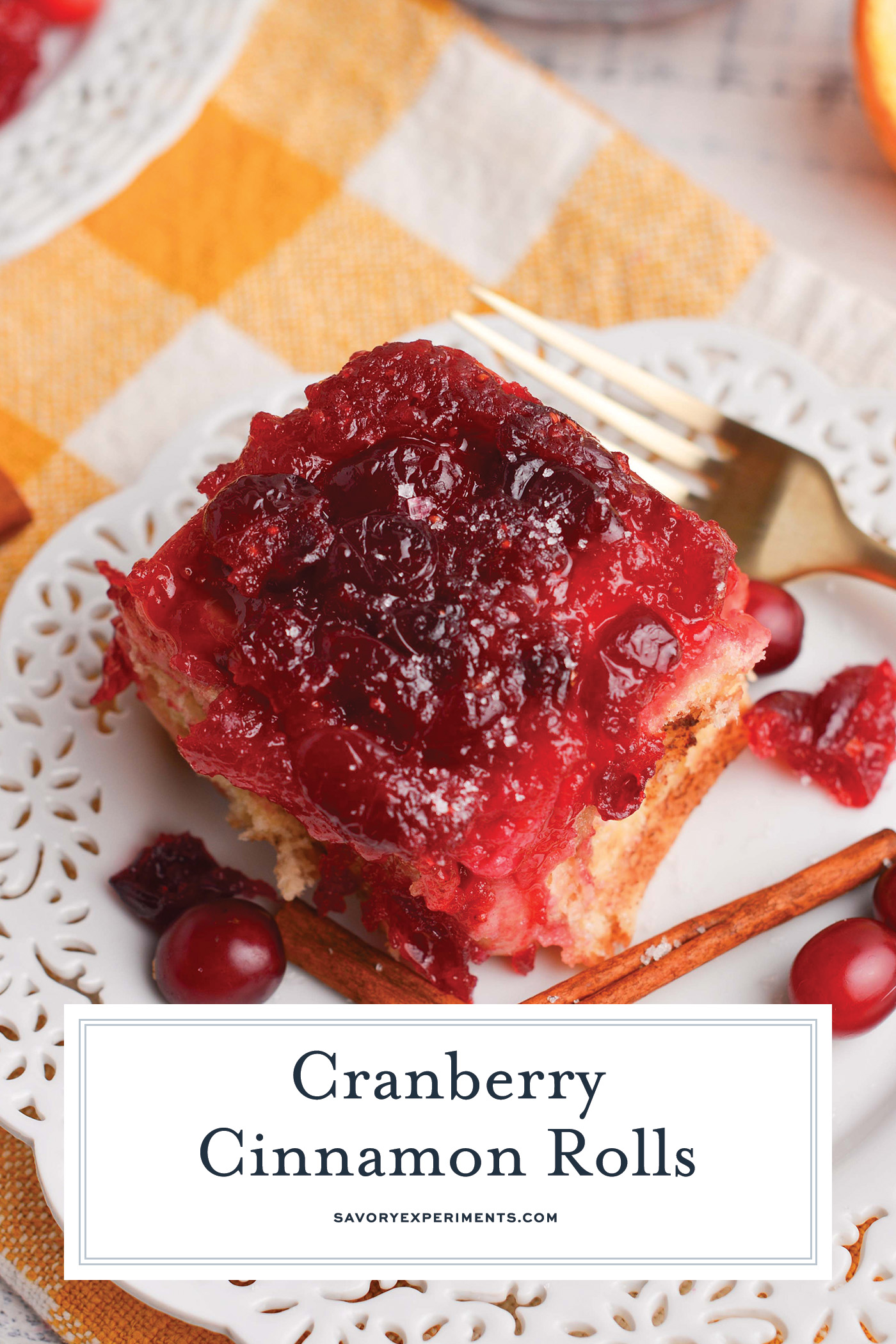 angled shot of cranberry cinnamon roll on plate with text overlay for pinterest