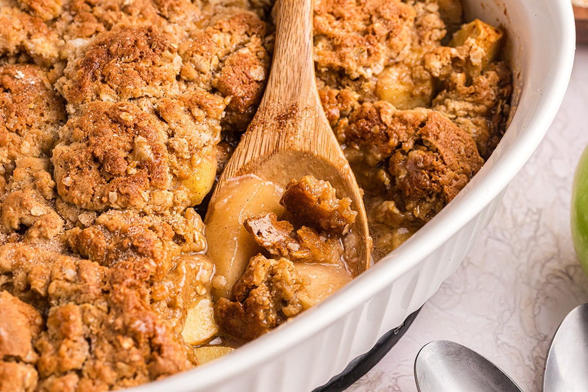 angled shot of wooden spoon in baking dish of apple crisp