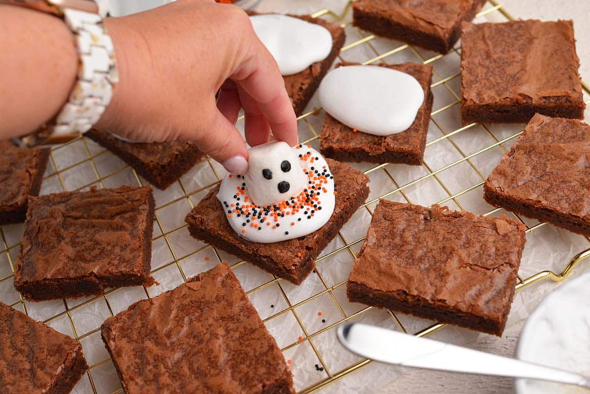 hand adding marshmallow to brownie