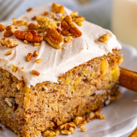 super close up slice of moist cake with frosting and pecan crumbles