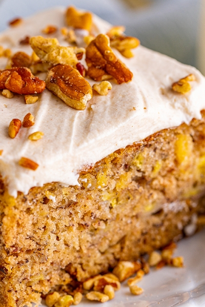 super close up slice of moist cake with frosting and pecan crumbles