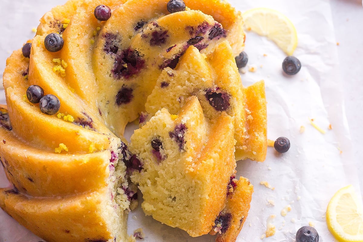 slices of cake with blueberries and lemon on white parchment paper