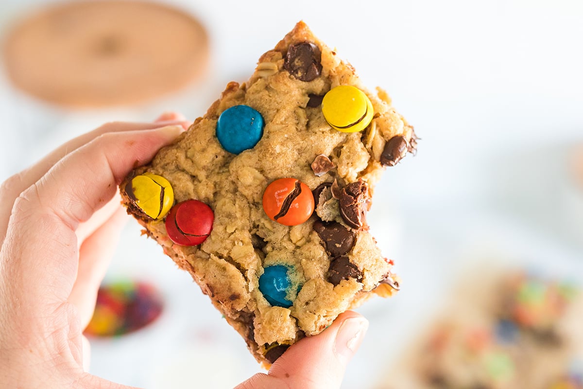 hand holding monster cookie bar with bite taken out of it