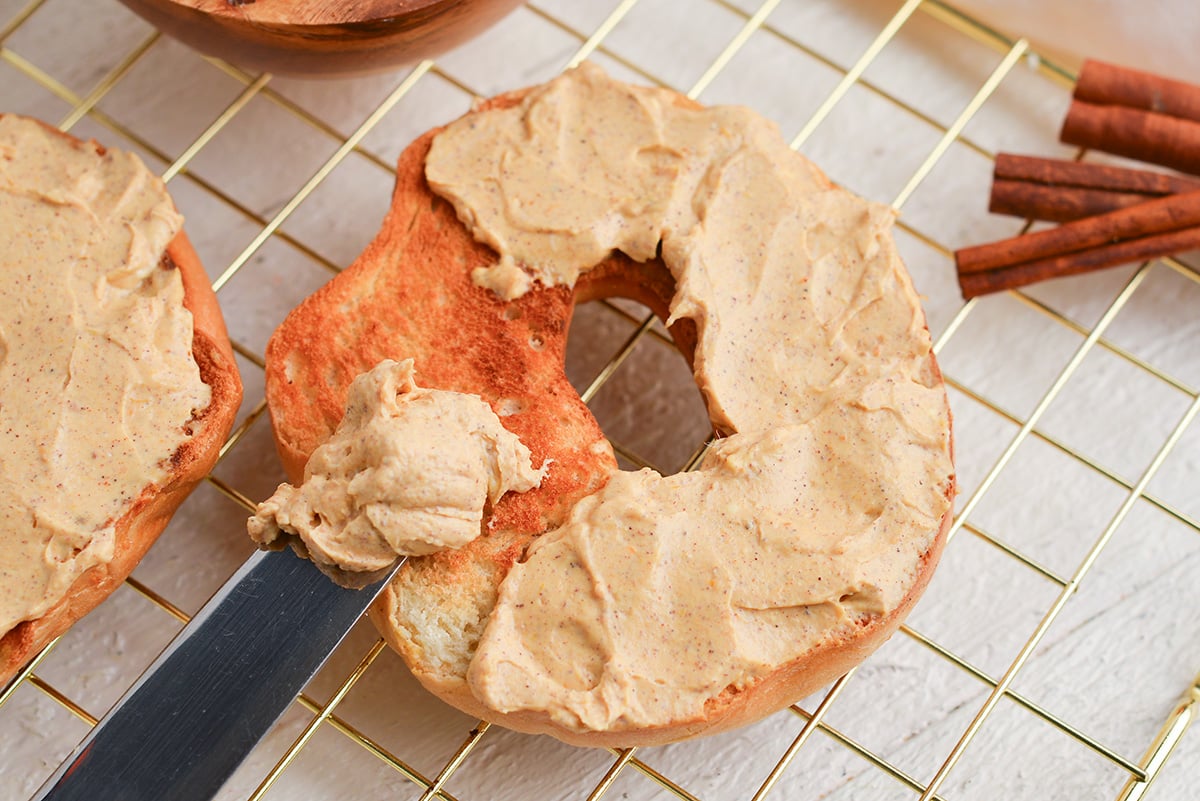 close up angled shot of pumpkin cream cheese spread onto bagel