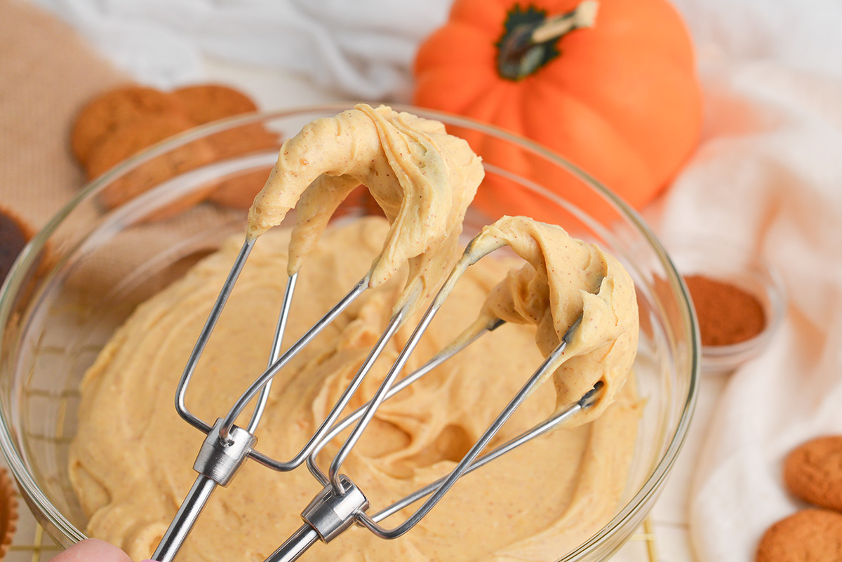 angled shot of pumpkin cream cheese frosting on beaters