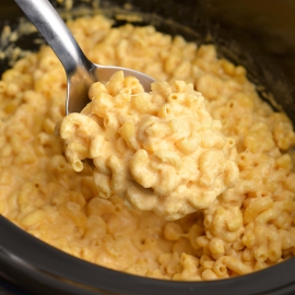 angled shot of serving spoon full of creamy mac and cheese