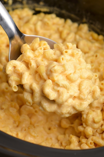 angled shot of serving spoon full of creamy mac and cheese