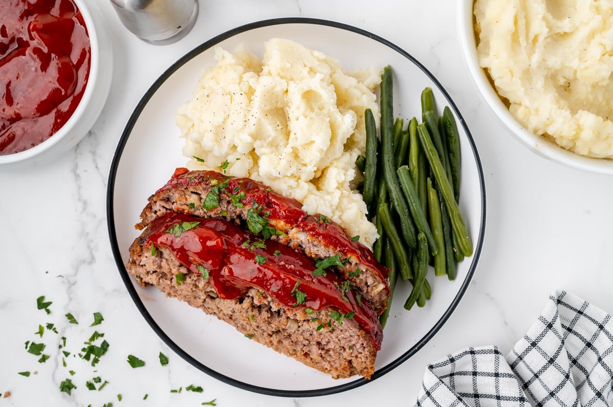 overhead shot of meatloaf slices with green beans and mashed potatoes