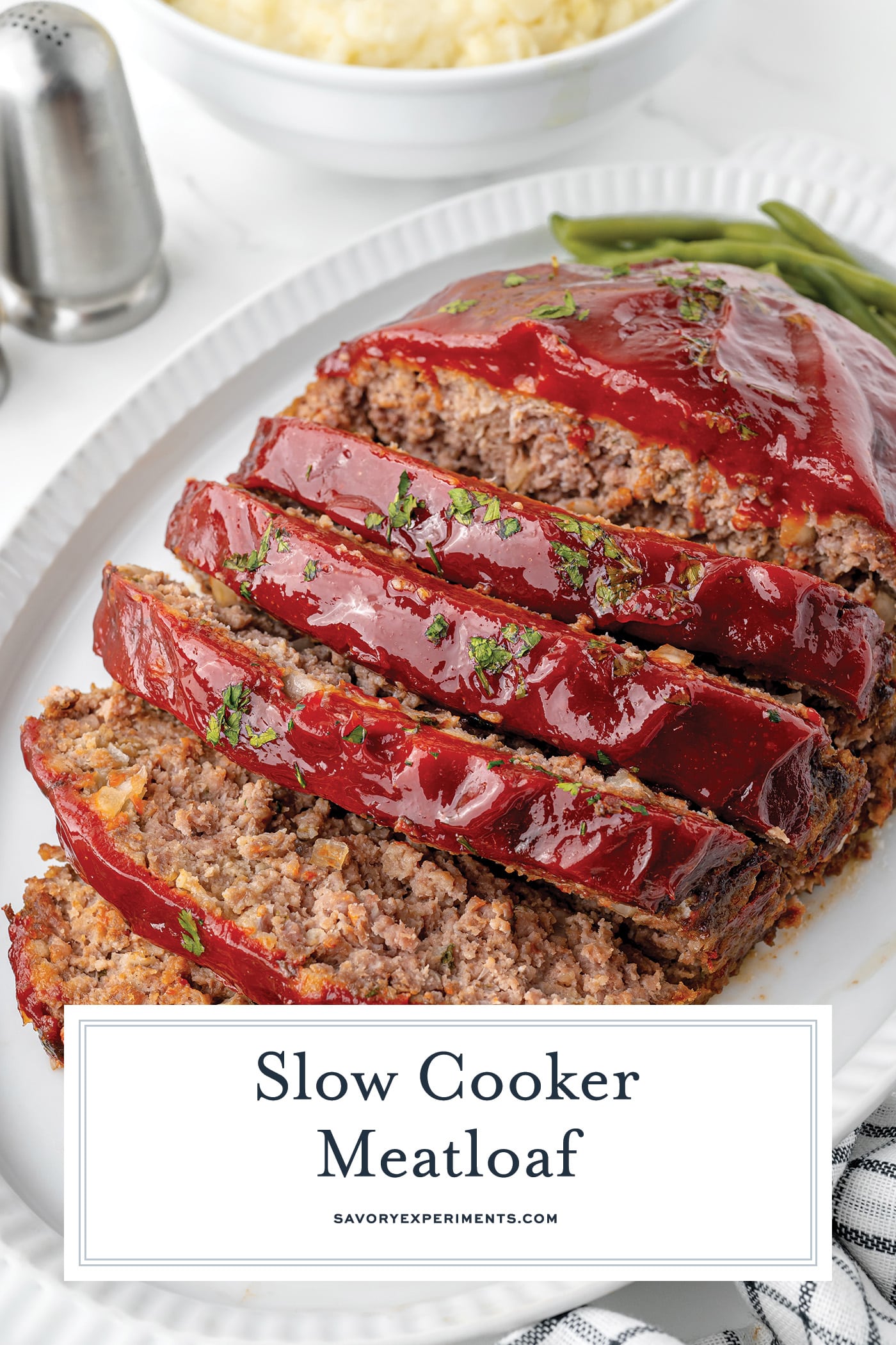 angled shot of sliced meatloaf on a platter with text overlay for pinterest