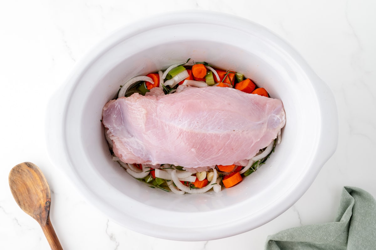 raw turkey breast over veggies in slow cooker