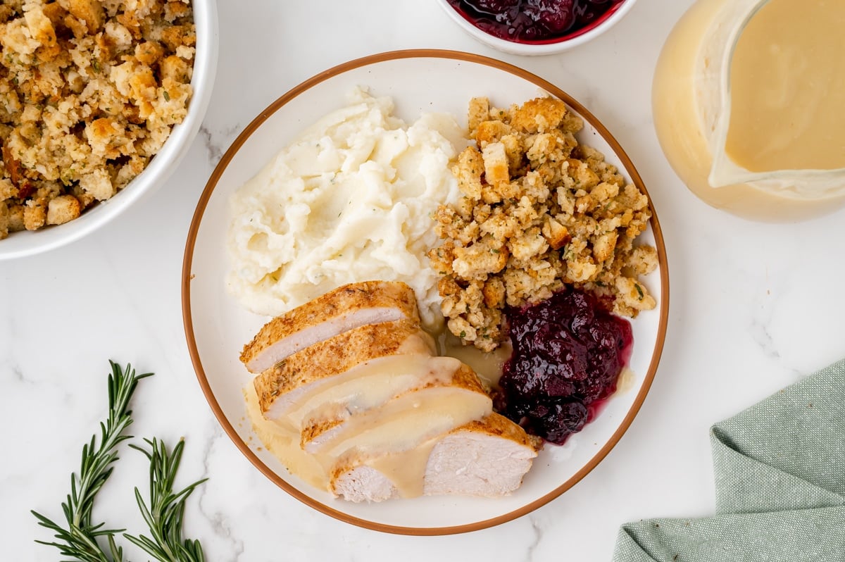 overhead shot of sliced slow cooker turkey breast on plate with potatoes and stuffing