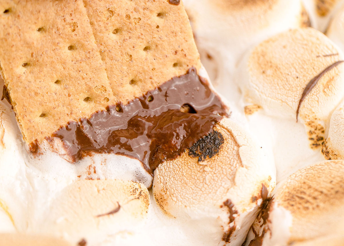 graham cracker dipping into melted chocolate and fluff